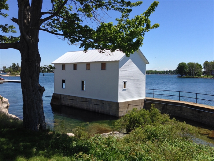 The boathouse has a fresh coat of paint on sides visible from the island.