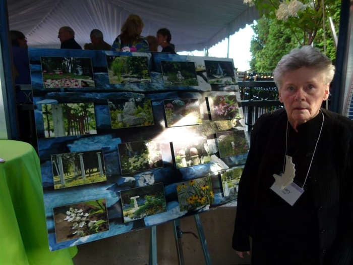 Guest of honor beside photographs of her magical garden. 